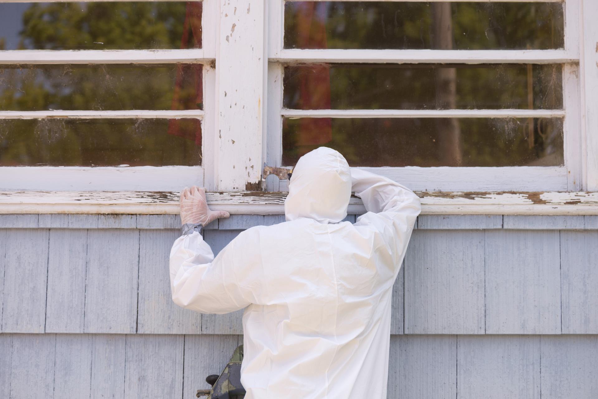 Hazmat worker cleaning paint from window