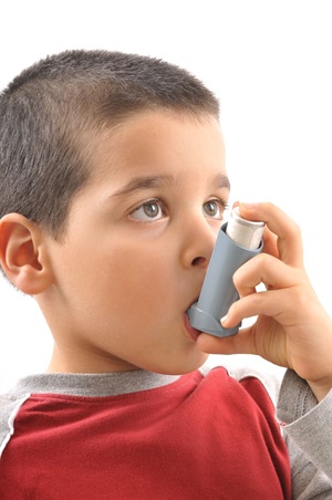 A child with a red shirt using an inhaler.
