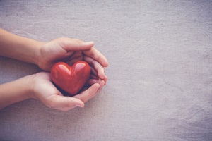 A picture of a person holding a small heart.