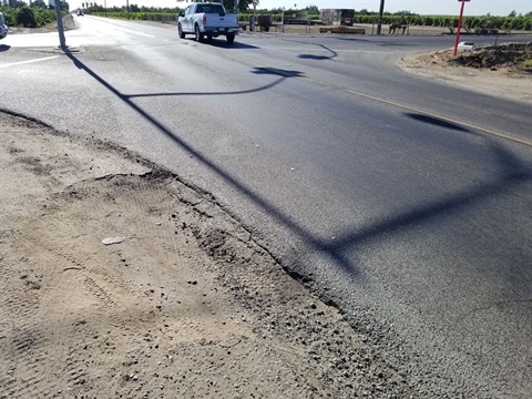 Image showing a rural road with a dirt shoulder with some tire marks.