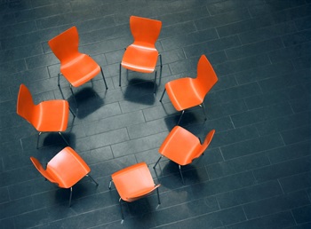 six orange chairs in a circle sitting on a black floor.jpg