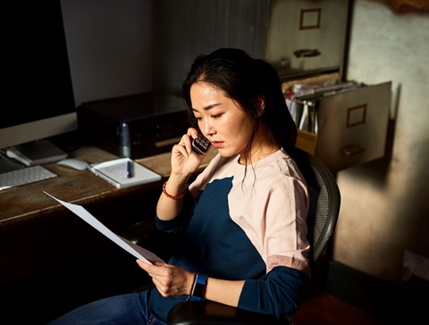 Asian woman in office holding paper calling on phone.jpg