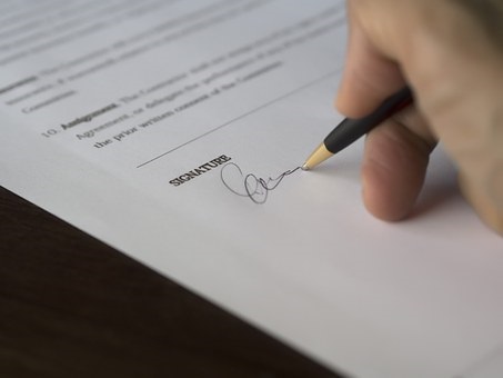 a person's hand signing a document